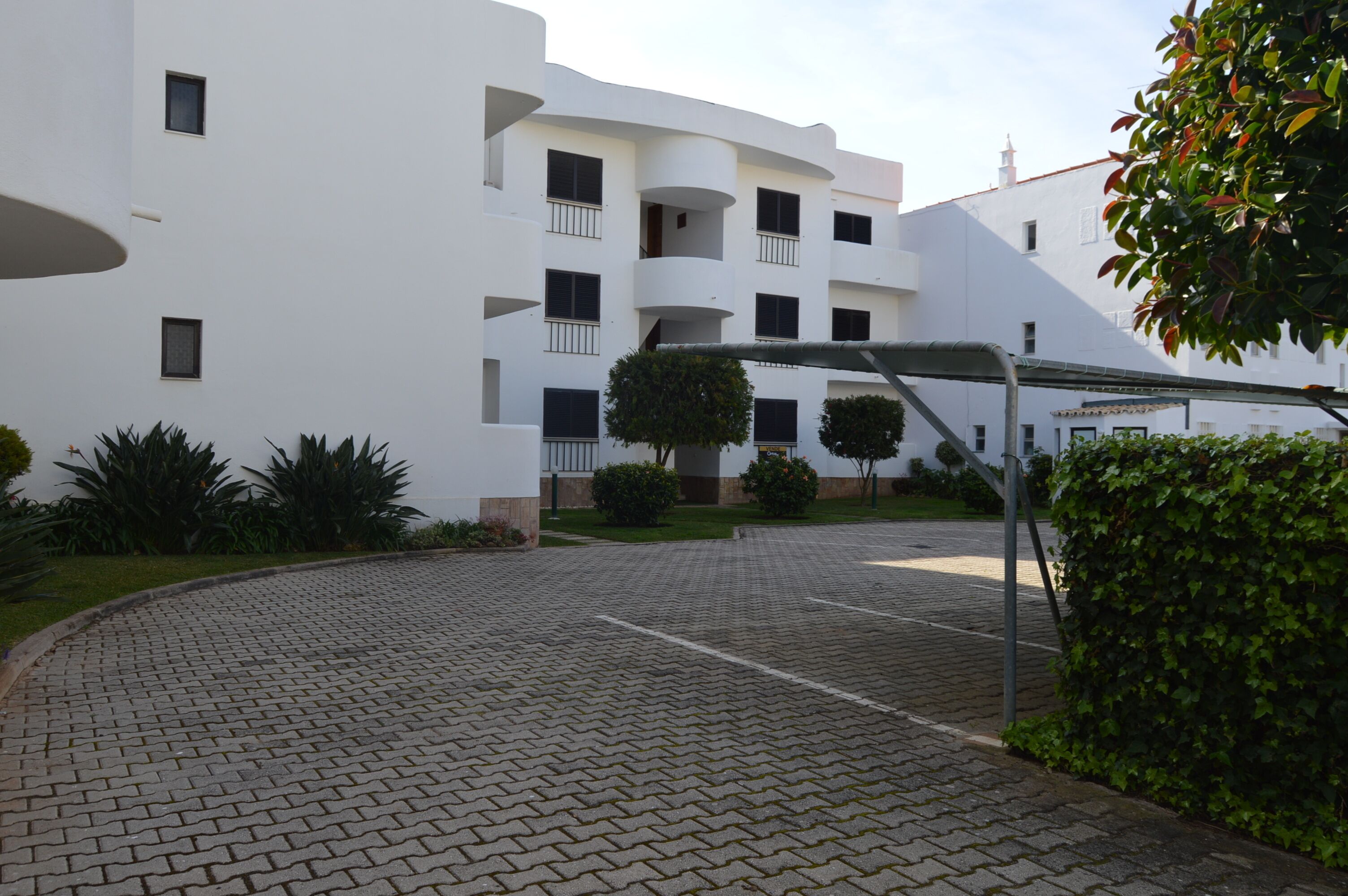 A modern building with a courtyard, paved walkways, and greenery.