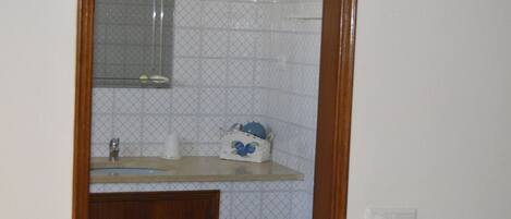 Une salle de bain avec un meuble en bois, un miroir et un lavabo sur lequel est posé un objet décoratif bleu.