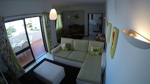 Un salon comprenant un canapé, un pouf et un coin repas avec des chaises et une table.