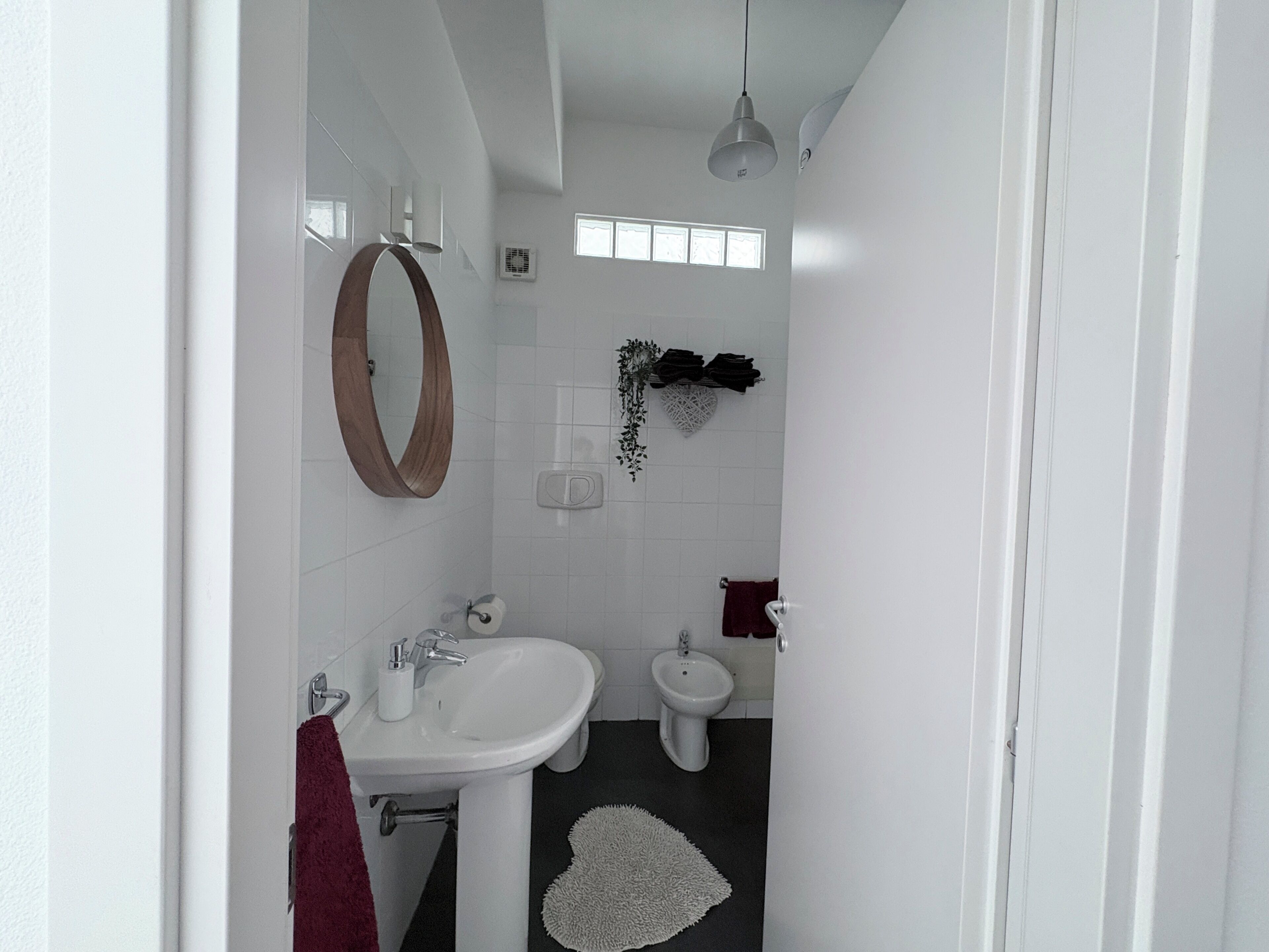 Un baño con un lavamanos blanco, un espejo, un bidé y un toallero.