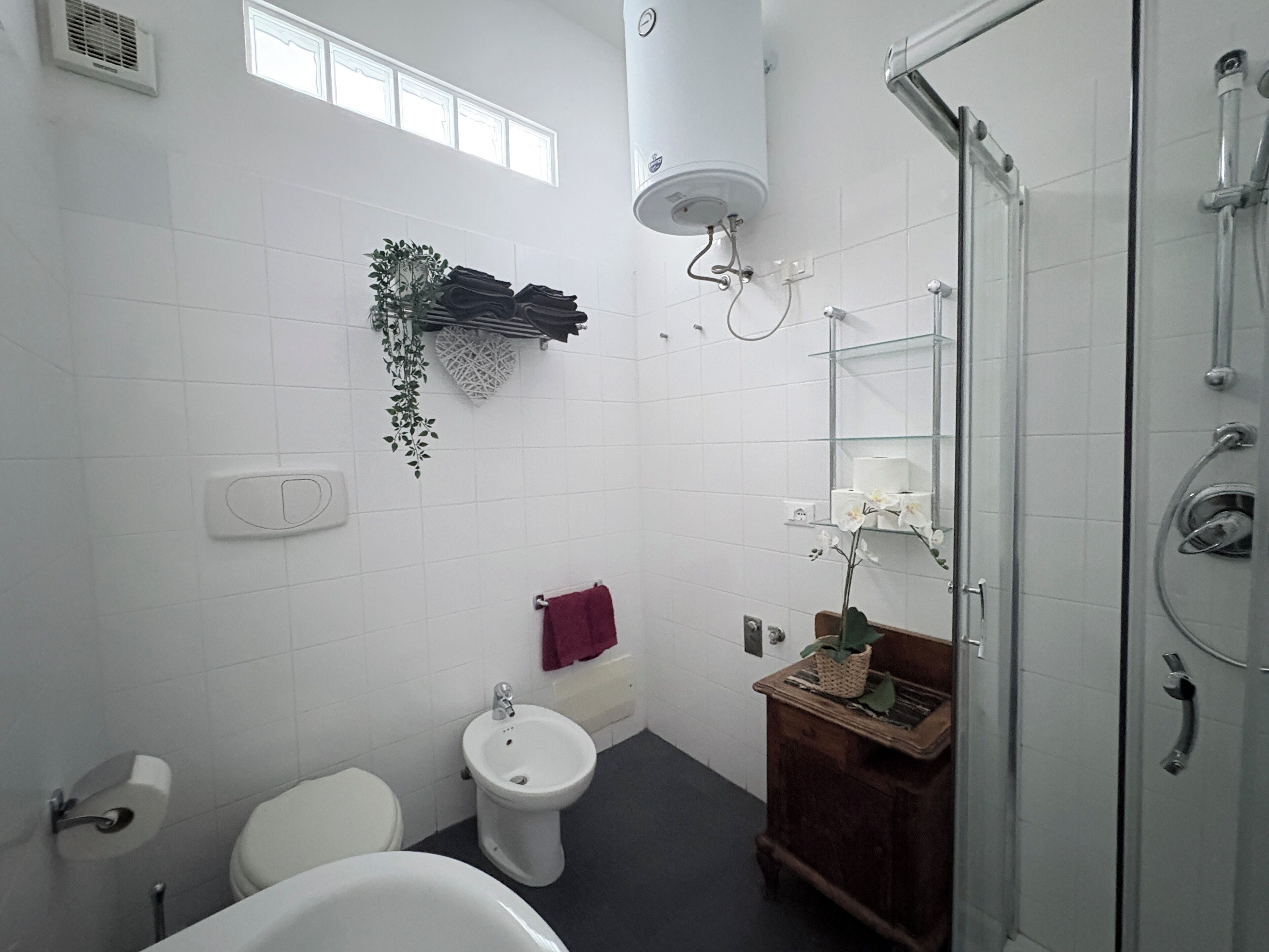 Une salle de bain comprenant des toilettes, un bidet, une baignoire et une douche à parois de verre.