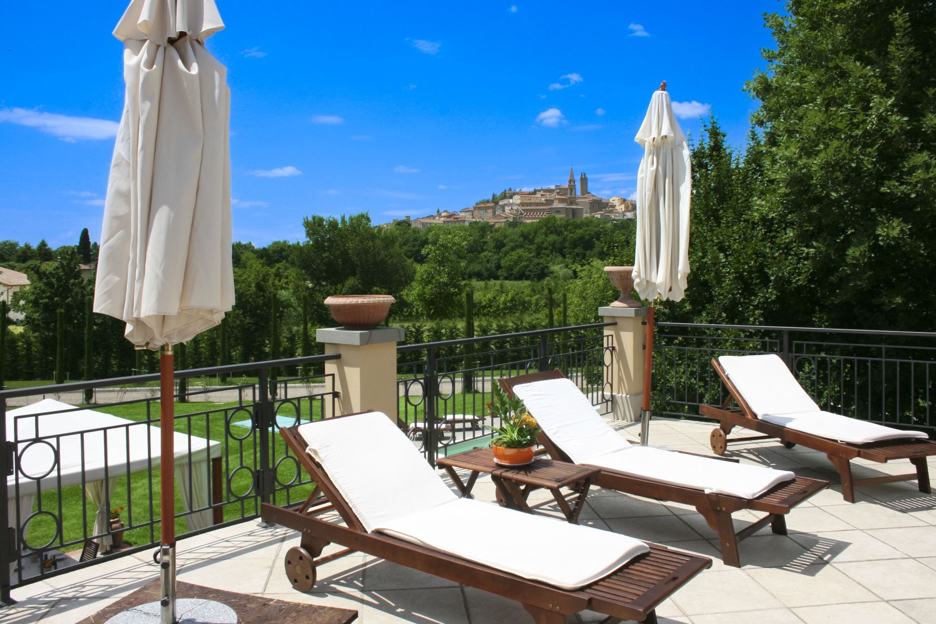 Une terrasse avec des chaises longues et des parasols, d’où l’on peut admirer un bâtiment historique en arrière-plan.