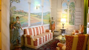 A room with a sofa, chairs, a lamp, and a statue.