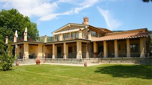 A large, two-story building with a stone facade, multiple balconies, and a spacious courtyard.