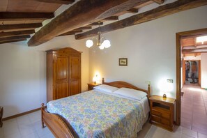 Ein Schlafzimmer mit einem hölzernen Bett, einem Nachttisch, einem Kleiderschrank und einer Chandelüster.