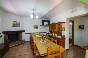 Ein Essbereich mit Holztisch, Stühlen, Kamin, Fernseher und Schrank.