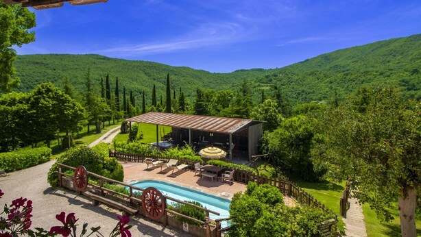 Una villa con piscina, area relax esterna e vista sulle colline verdi.