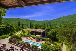 Une villa avec piscine, un espace salon extérieur et une vue sur des collines verdoyantes.