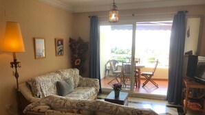 Un salon avec un canapé, une table basse, une lampe et une vue sur l’extérieur.