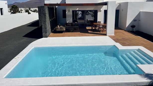 Une maison moderne dotée d’une piscine, d’un espace salon extérieur et offrant une vue sur les montagnes.