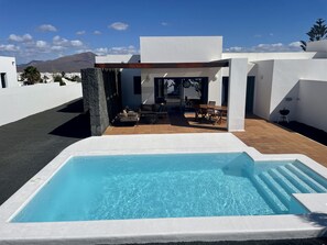 A modern house with a swimming pool, outdoor seating, and a mountain view.