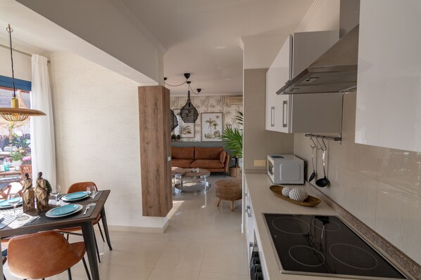 A modern kitchen with a dining area, featuring a wooden table, chairs, and a sofa.