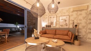 Un salon moderne avec un canapé, deux petites tables rondes et des lampes suspendues en osier.