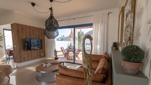 Un salon moderne avec un canapé, une table basse ronde et un téléviseur fixé au mur.