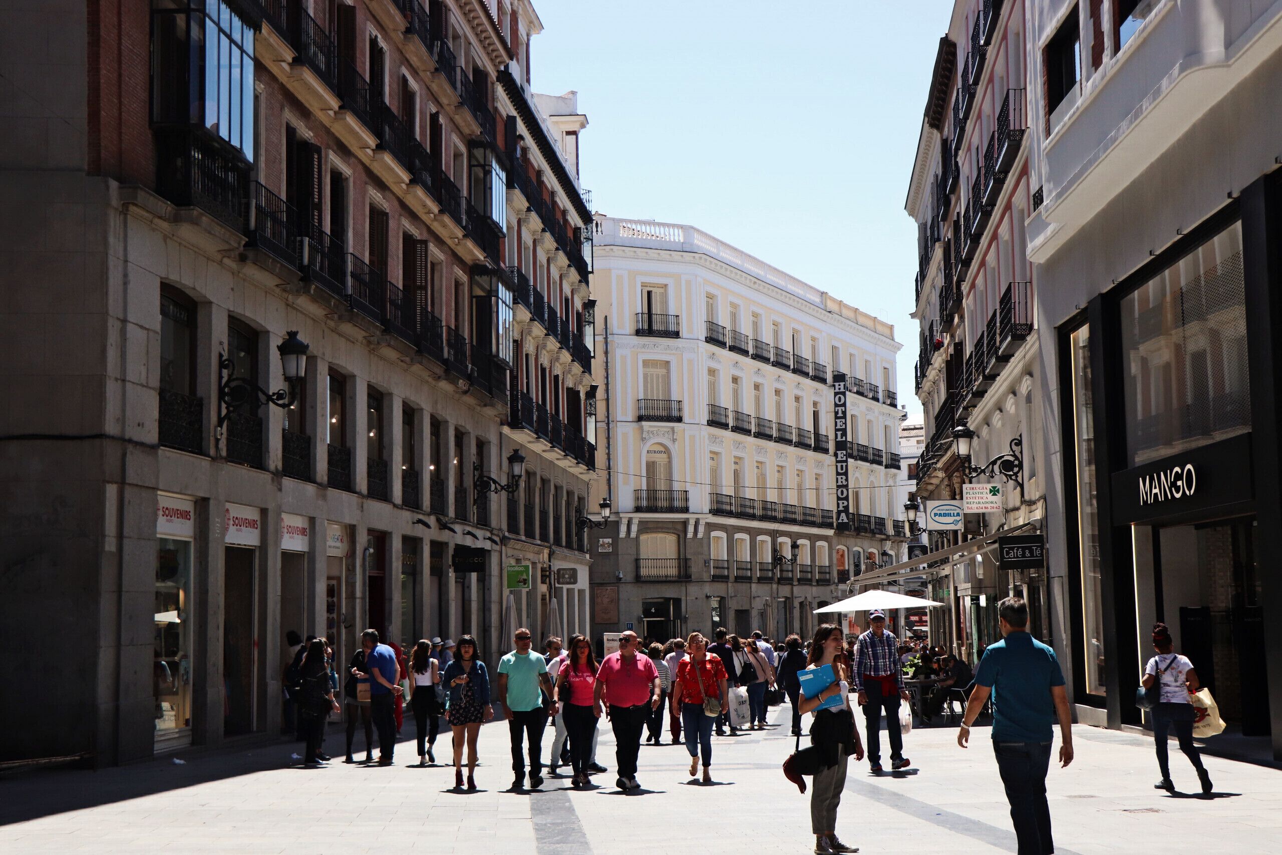 A bustling street with a hotel named 'MANGO' on the right.