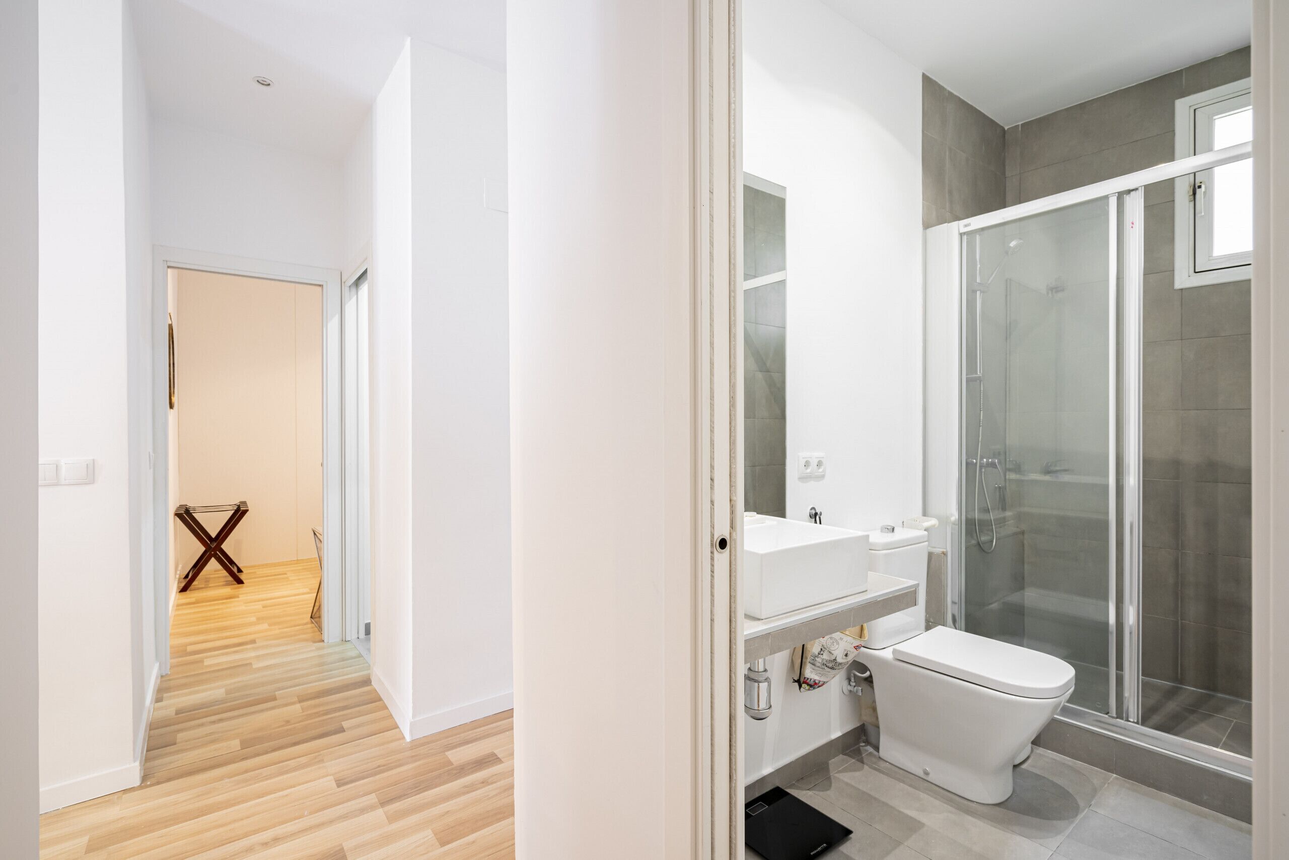 Une salle de bain moderne avec une douche à parois de verre, un lavabo blanc et des toilettes.