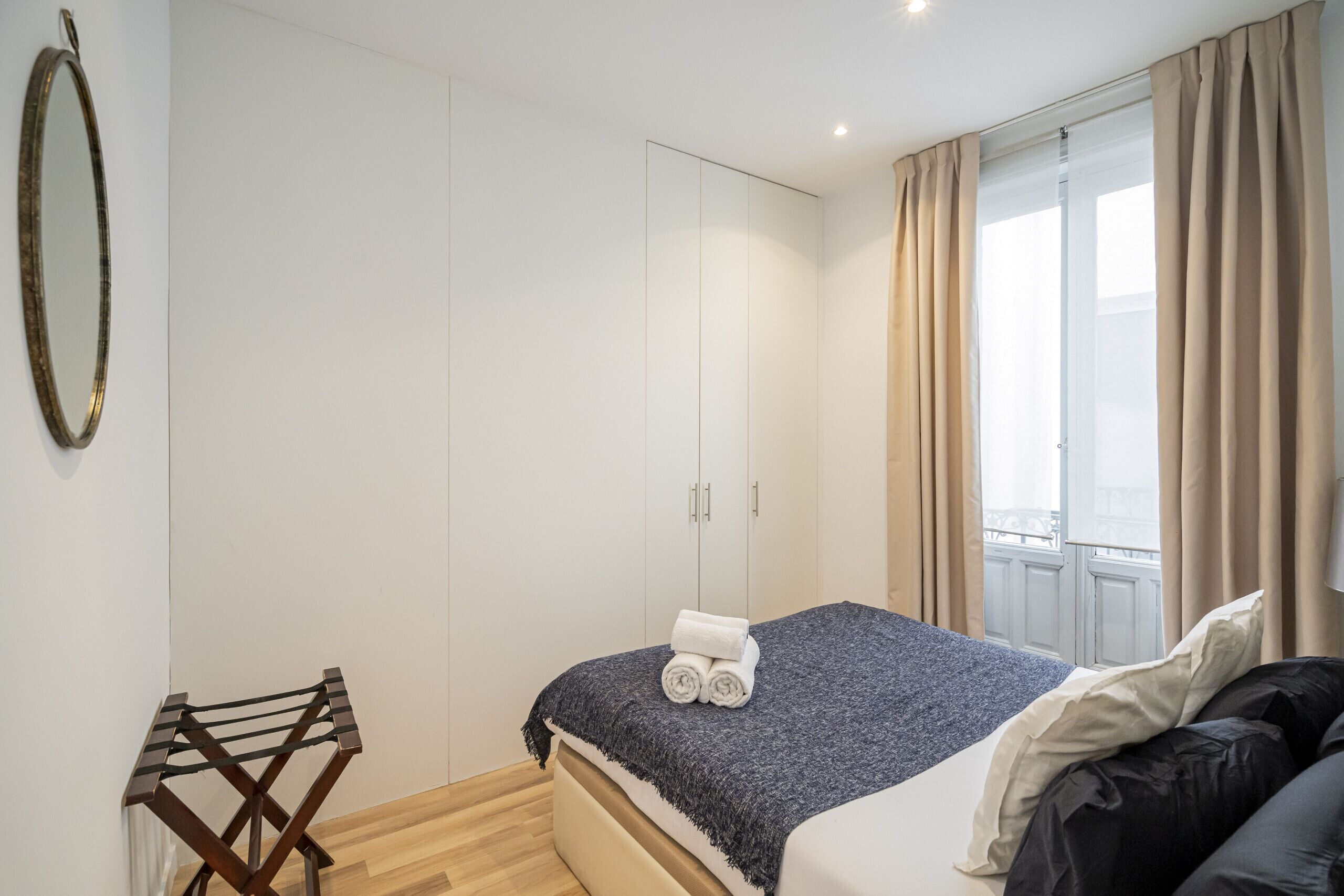 Een slaapkamer met een bed, een kledingkast en een raam met gordijnen.