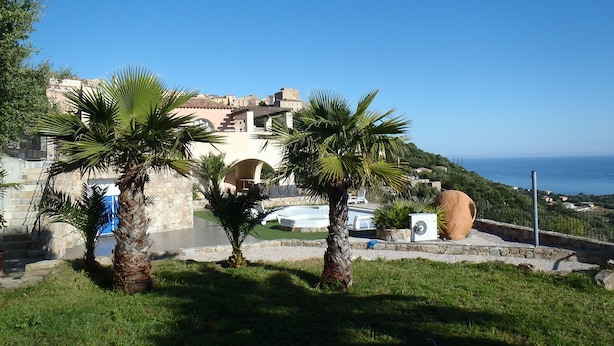A coastal view with a stone building, palm trees, and a clear sky. - House / Villa - MONTICELLO (Monticello)
