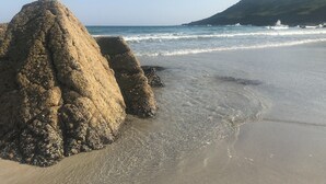 Een strand met grote rotsformaties en een helder uitzicht op de oceaan.