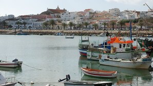 A harbor with boats docked, a rocky breakwater, and buildings in the background. - SEA VIEW, SWIMMING POOL, PARKING AND 250 MTRS. THE MARINA AND BEACH (LAGOS)