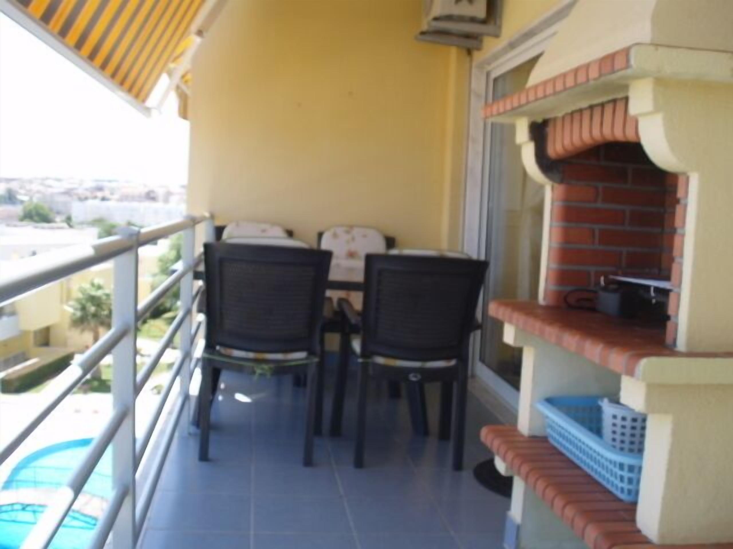 Ein Balkon mit Tisch und Stühlen, einem Backofen und Blick auf die Stadt.