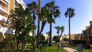 A courtyard with palm trees, a paved walkway, and a building with balconies. - SEA VIEW, SWIMMING POOL, PARKING AND 250 MTRS. THE MARINA AND BEACH (LAGOS)