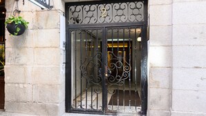 A black wrought iron gate with a number "2" above it, leading to a building entrance.