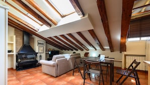 Acogedor dormitorio en el ático con chimenea, sofá, mesa de comedor y sillas.