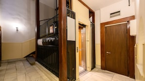 Un pasillo con piso de mármol, un ascensor y una puerta de madera.