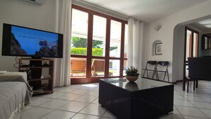 Una sala de estar con televisor, sofá, mesa de centro y comedor con sillas.