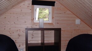 A small, wooden-paneled room with a sloped ceiling, a window with a black valance, and a central table with a black top and two black drawers. - Cozy cottage near the lake, including free Wi-Fi and own rowing boat (Hallaryd)