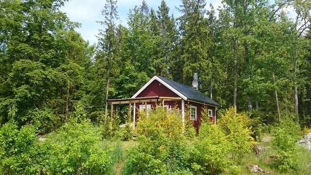 A small cabin with a red roof and white trim, surrounded by dense forest and greenery. - Cozy cottage near the lake, including free Wi-Fi and own rowing boat (Hallaryd)