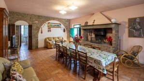 Un comedor con una mesa larga, sillas, una chimenea y un arco de piedra.