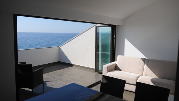 Un balcón moderno con vista al mar, un sofá y una mesa.