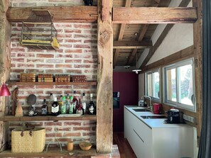 Een landelijke keuken met open bakstenen muren, houten balken en een wit aanrecht.
