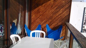 A dining area with a white table and chairs, a wooden accent wall, and a glass railing overlooking a cityscape. - Apartment in residence at the foot of the slopes in Tignes Lac promotion 11/18:02 (Tignes)