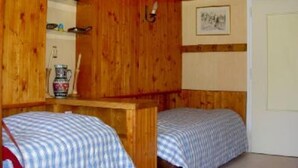 A room with wooden walls, two beds with checkered bedding, a small table with a pitcher, a shelf with items, and a framed picture on the wall. - Apartment in residence at the foot of the slopes in Tignes Lac promotion 11/18:02 (Tignes)