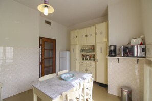 Una cocina compacta con encimera de mármol, un refrigerador y una cafetera.