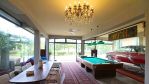 A spacious living room with a pool table, a dining area with a long table and chairs, a chandelier, and a large window offering a view of the outdoors. - Charming historic villa near Arezzo, with private pool adorned with marble, centuries-old park, and (Arezzo)