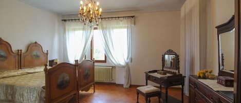 Un dormitorio con una cama de madera, un aparador, un escritorio, un espejo y una araña.