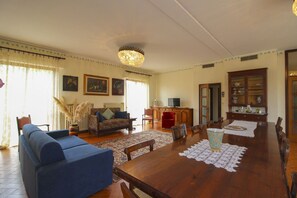 Een ruime woonkamer met een houten eettafel, banken en een kroonluchter.