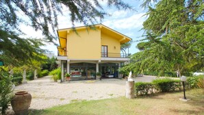 A yellow two-story building with a balcony, surrounded by greenery and a gravel driveway. - Charming historic villa near Arezzo, with private pool adorned with marble, centuries-old park, and (Arezzo)