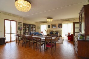 Un salón comedor espacioso, con ventanas amplias y una araña.