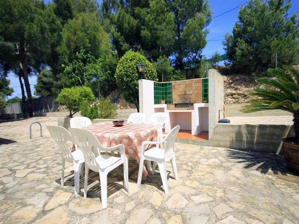 A patio with a table and chairs, a stone floor, and a small outdoor kitchen area with a tiled backsplash.