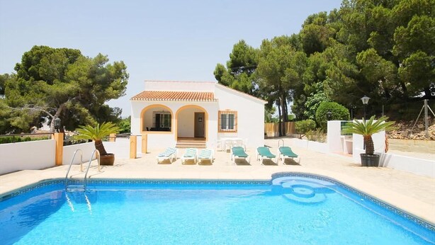 A pool area with a small building, lounge chairs, and potted plants. - Caleta - Javea, Costa Blanca (Javea)