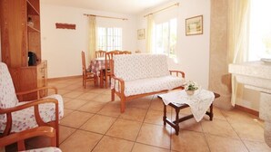 A cozy living room with a sofa, chairs, a dining table, and a kitchen area with a sink and counter. - Caleta - Javea, Costa Blanca (Javea)
