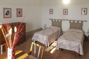 A bedroom with two beds, a wooden dresser, a chair, and wall art.