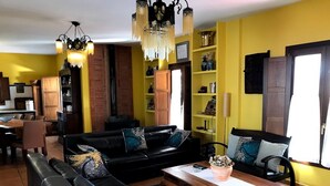 Un salon avec un canapé en cuir noir, une table basse en bois et un mur jaune.