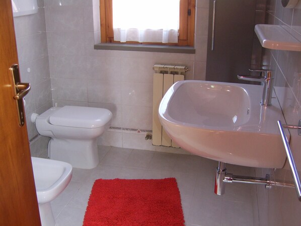 A bathroom with a toilet, a bathtub, a red rug, and a window with curtains. - Apartment/ flat - Marina di grosseto (Marina di Grosseto)