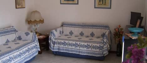 A living room with two sofas, a lamp, and framed pictures on the wall.